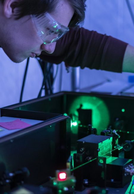 A scientist leans over an optical table while doing research on quantum information systems